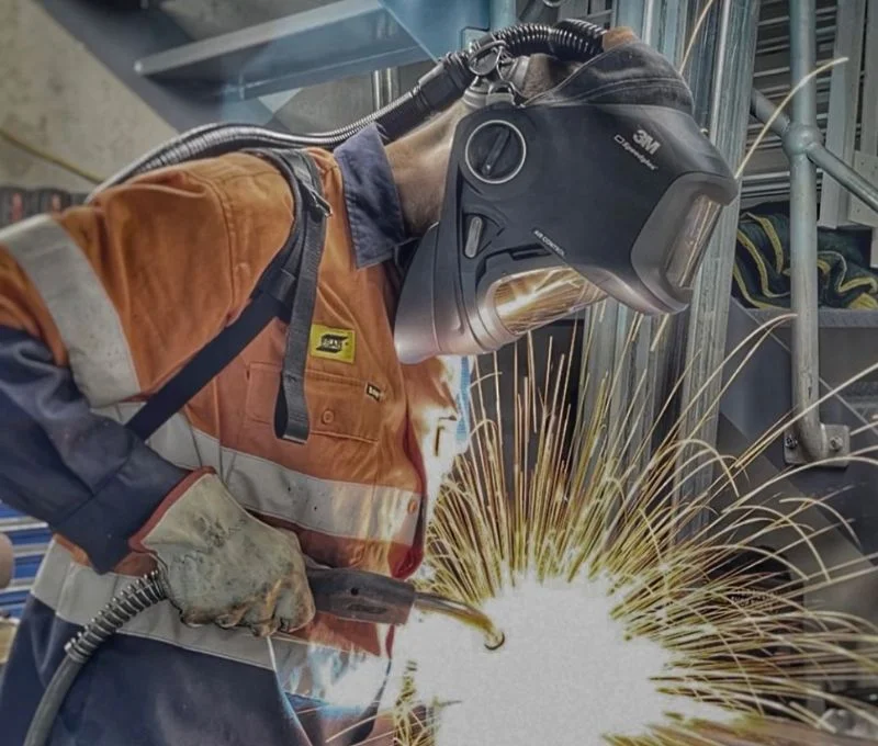 Worker wearing safety welding mask and clothes while welding