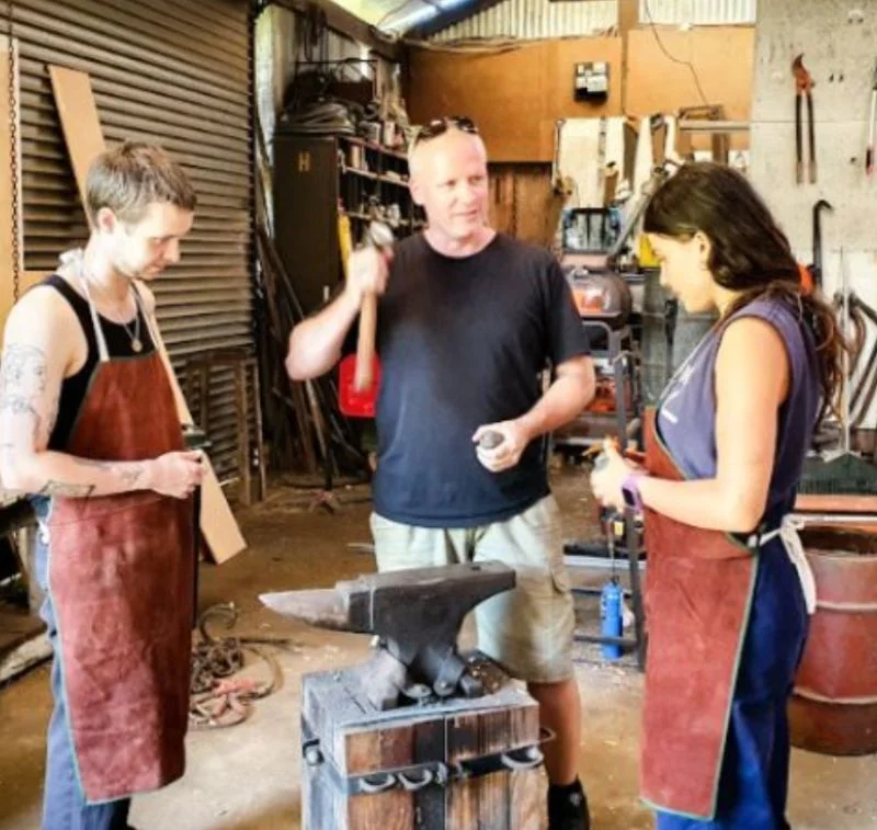 Mentor teaching how to do blacksmithing