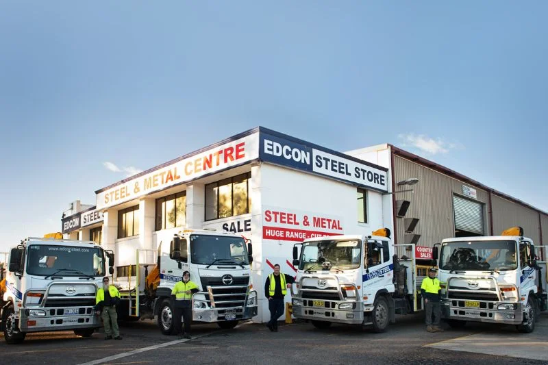 Big trucks and employees outside a metal store