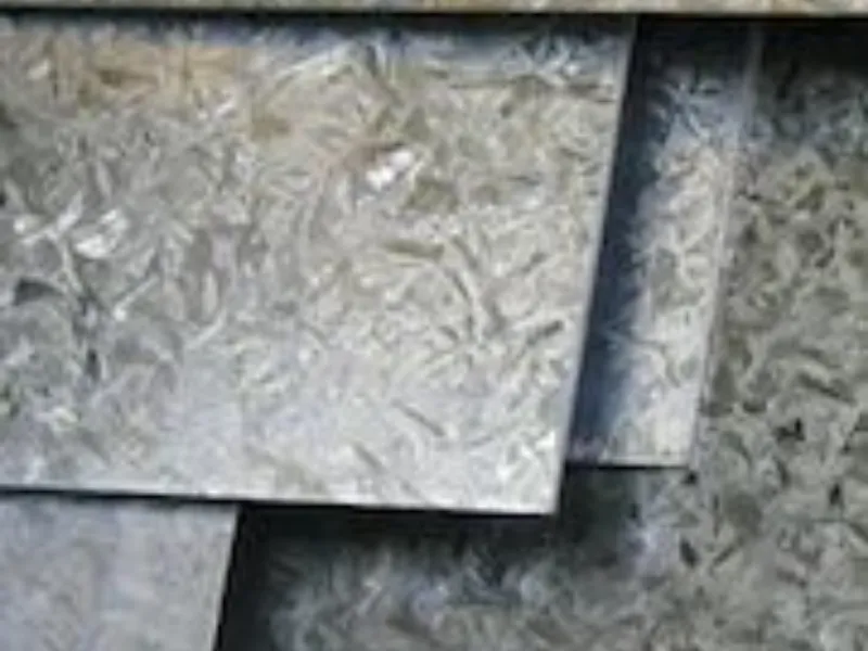 Stacked sheets of Galvabond steel with a distinctive silver, spangled galvanised pattern across the surface.