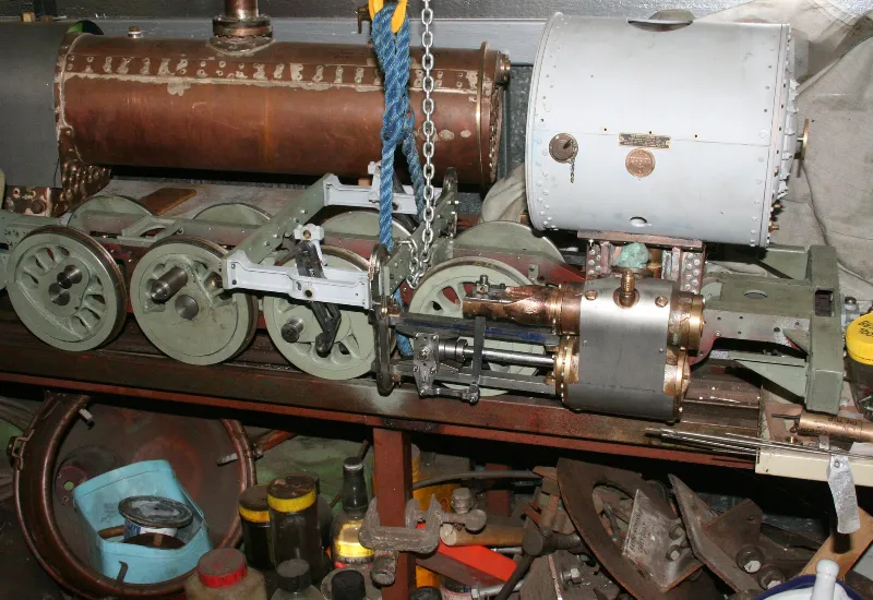 Side view of a partially assembled model steam locomotive on a workshop bench