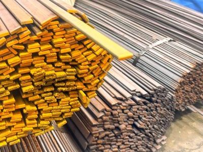 Stacks of yellow-coated metal bars and long steel rods stacked in a yard.