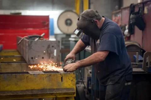 male wearing PPE welding metal in a workshop
