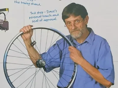 Metalwork Inventor David holds up a custom bike wheel