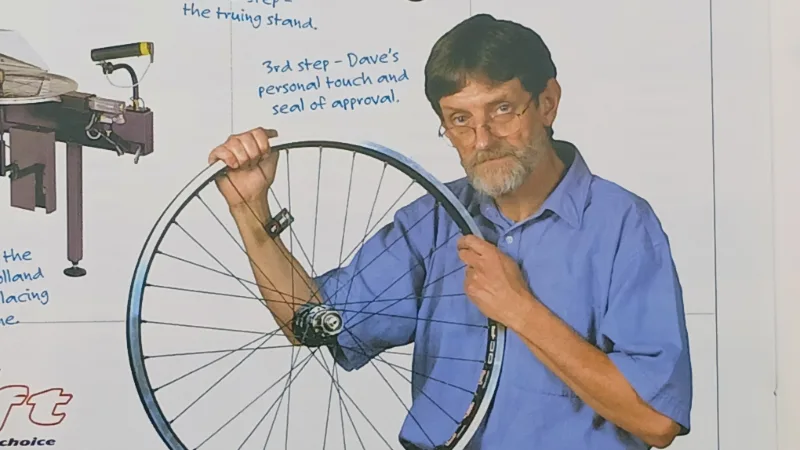 Metalwork Inventor David holds up a custom bike wheel